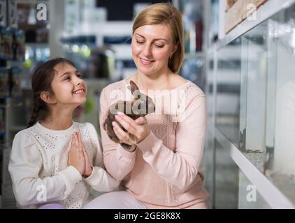 Mother with her daughter holding rabbit together at pet store Stock Photo