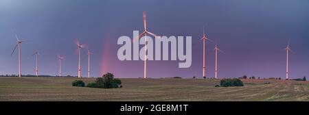 Red rainbow after passing an evening storm over a farm windmills Stock Photo