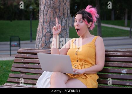 Young caucasian woman with pink hair having a great idea in front of a laptop. Stock Photo