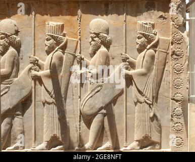 Soldiers of historical empire with weapon in hands. Stone bas-relief in ancient city Persepolis, Iran. Capital of the Achaemenid Empire (550 - 330 BC) Stock Photo
