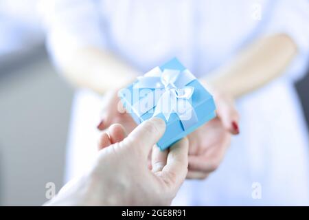 Man hand passes gift box to woman Stock Photo