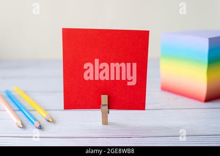 Blank Sticky Note With Laundry Clip Stack Of Colorful Paper Pen Placed On Table. Empty Piece Of Sheet Clipped Beside Pen And Flashy Papers On Desk. Stock Photo