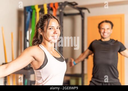 Woman stretching her arms back while looking at the camera with a man behind her Stock Photo