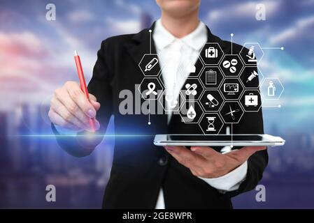 Lady In Uniform Standing Holding Tablet And Virtually Typing With Pen. Business Woman Carrying Pad Typing And Displaying New Futuristic Technologies. Stock Photo