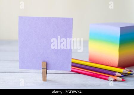 Blank Sticky Note With Laundry Clip Stack Of Colorful Paper Pen Placed On Table. Empty Piece Of Sheet Clipped Beside Pen And Flashy Papers On Desk. Stock Photo