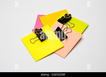 Different colored blank sticky notes with black binders on white background Stock Photo