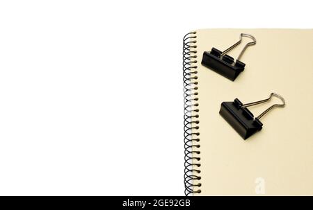 Two black metal binder paper clips on a notebook with white space Stock Photo