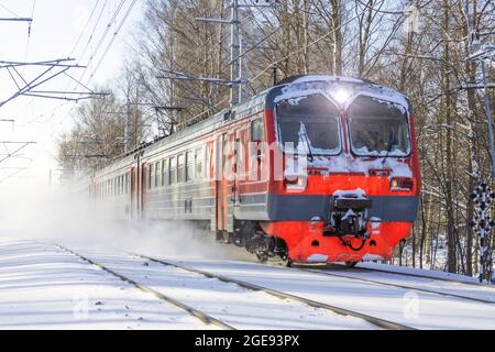 Electric suburban train drives passing by through a snowy park Stock Photo