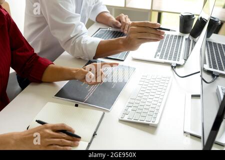 Two programmers are discussing on creen work with computer code paper on office table. Stock Photo