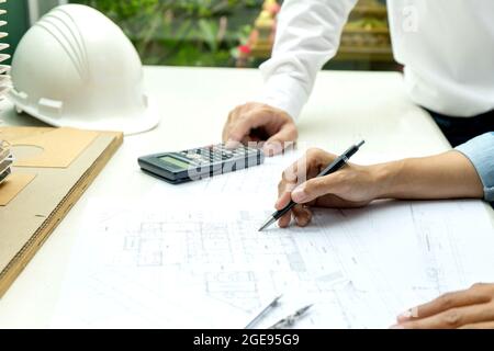 Engineers and architects are discussing and revising plans for building construction projects on floor plans and building models. Stock Photo