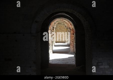 A through corridor through the casemates of the defensive barracks in the rays of sunlight. Arch. artistic noise Stock Photo