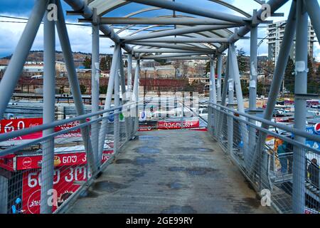 A bridge made of round metal pipes across the road. Tbilisi, Georgia - 03.19.2021 Stock Photo