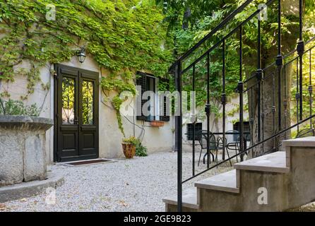 Facade of a house facing its courtyard with its walls covered by ivy Stock Photo