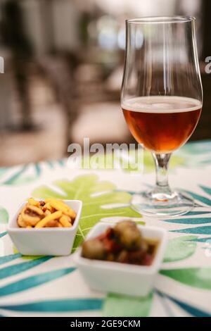 Glass of beer with tapas, olives, and snacks on a table Stock Photo