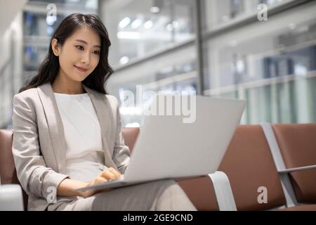 Young Chinese businesswoman using laptop in airport Stock Photo