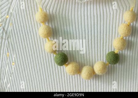 Handmade wool necklace on the background of clothes. Stock Photo