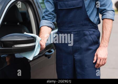 Cropped view of mechanic cleaning wing mirror of car outdoors Stock Photo