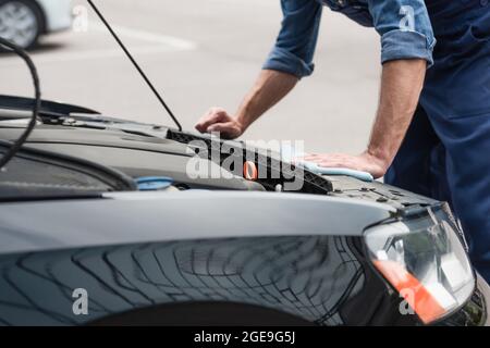 Cropped view of mechanic with rag cleaning car outdoors Stock Photo