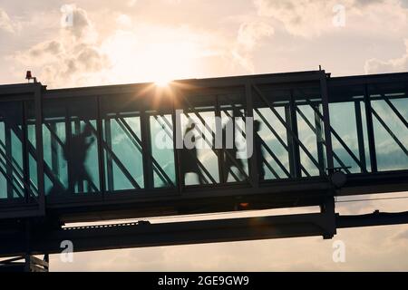 Silhouettes of people walking at busy airport. Passengers walking inside boarding bridge. Stock Photo