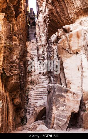 Steps cut through a narrow gap in the canyon of Siq Al-Barid or Little Petra in Jordan Stock Photo
