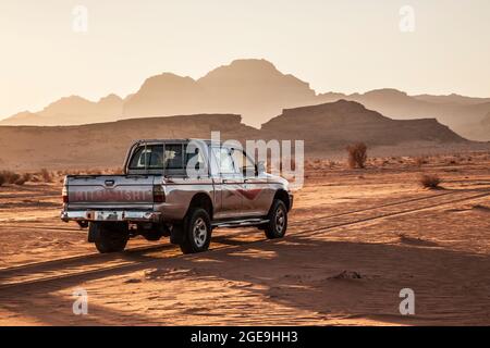 A Mitsubishi tourist jeep at sunset in the Jordanian desert at Wadi Rum or Valley of the Moon. Stock Photo