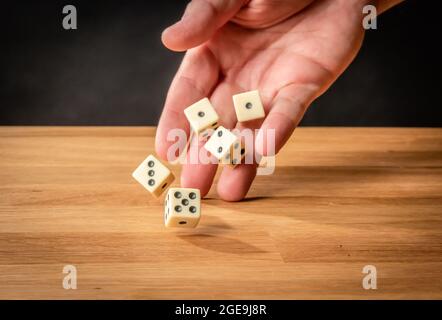 Hand throwing five dice on a wooden table Stock Photo