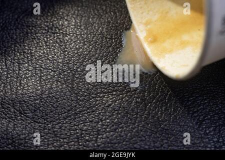 coffee spill from a paper cup, on black leather texture, cleaning concept macro, selective focus Stock Photo