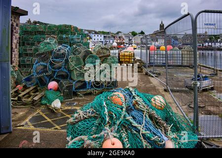 On a grey and overcast afternoon, fishing nets and lobster pots line the quay side in Tarbert Stock Photo