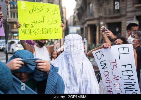 Barcelona, Catalonia, Spain. 17th Aug, 2021. Protester is seen wearing a burqa and another is seen removing the burqa.Around a hundred women have participated in a feminist demonstration in front of the United Nations headquarters in Barcelona to demand an urgent international response to protect Afghan women and girls. (Credit Image: © Thiago Prudencio/DAX via ZUMA Press Wire) Credit: ZUMA Press, Inc./Alamy Live News Stock Photo