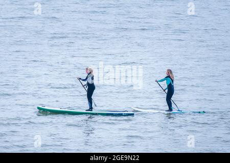 Two women paddle boarding on the sea. Stock Photo