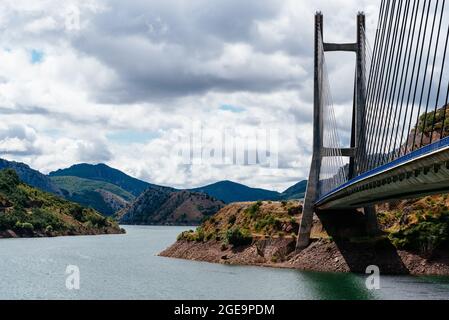 Modern suspension bridge across reservoir Los Barrios de Luna in Castile and Leon, Spain. Carlos Fernandez Casado Bridge Stock Photo