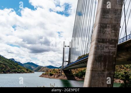 Modern suspension bridge across reservoir Los Barrios de Luna in Castile and Leon, Spain. Carlos Fernandez Casado Bridge Stock Photo