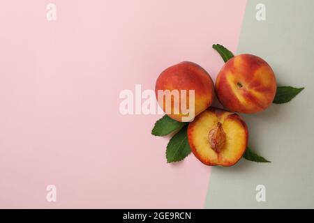 Ripe peach fruits with leaves on two tone background Stock Photo