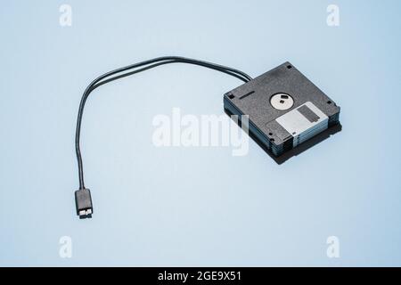 From above of stack of black floppy disks with usb cable placed on light blue background Stock Photo
