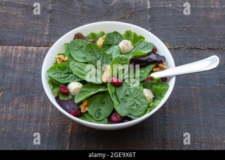 High angle of delicious salad with spinach and beans and walnuts served in bowl on wooden table for healthy lunch Stock Photo