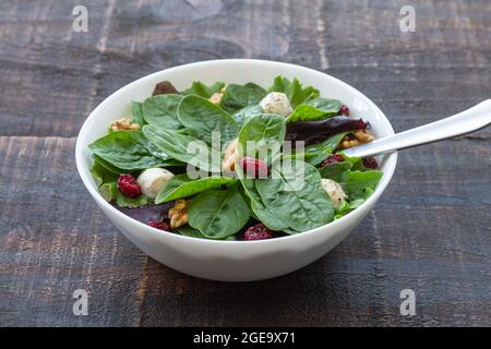 High angle of delicious salad with spinach and beans and walnuts served in bowl on wooden table for healthy lunch Stock Photo