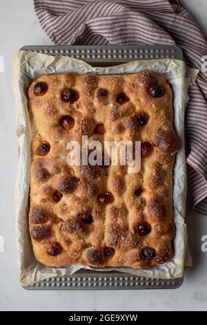 Top view of freshly baked traditional bread with tomatoes placed on baking paper Stock Photo