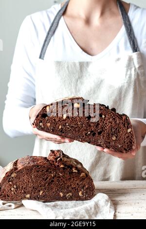 Crop faceless Woman hands holding freshly baked sourdough rye bread Crumb pan cutting in half Stock Photo