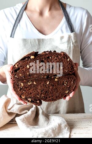 Crop faceless Woman hands holding freshly baked sourdough rye bread Crumb pan cutting in half Stock Photo