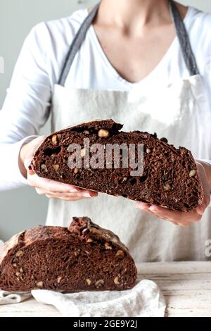 Crop faceless Woman hands holding freshly baked sourdough rye bread Crumb pan cutting in half Stock Photo