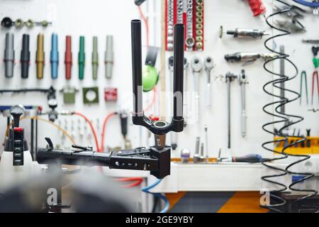 For of modern bicycle attached to rack near wall with assorted instruments in modern workshop Stock Photo