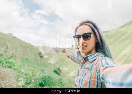 Young smiling woman in sunglasses makes selfie photo. Stock Photo