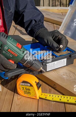 Close up of man selecting screw for cordless screwdriver. Stock Photo