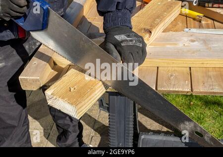 Close up of man using handsaw to cut piece of wood. Stock Photo