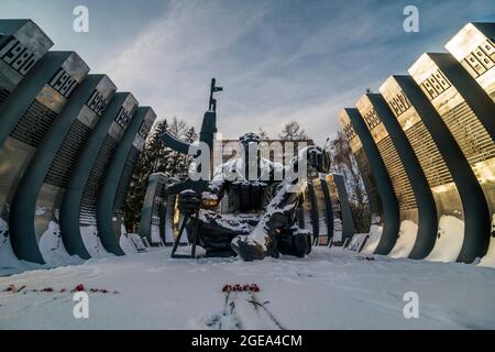Roses grace the freshly fallen snow in front of the Afghanistan War Memorial known as the Black Tulip in downtown Ekaterinburg in Russia. Stock Photo