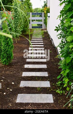 Sidewalk made from concrete blocks along the wall of a house in the garden. Stock Photo