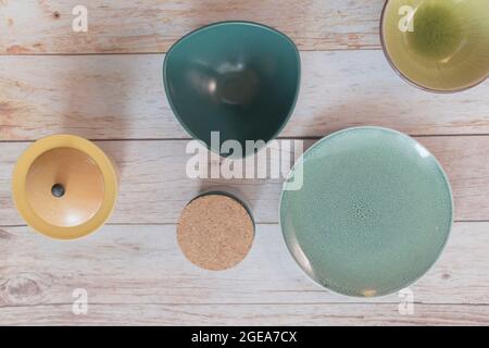 Turquoise, green and yellow porcelain, ceramic plates and bowls on a wooden background. Top view, space for text, article layout design. Stock Photo