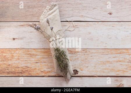 Folded a natural color linen dinner napkin and dry lavender sprigs on wooden table. Top view, copy space, flat lay, space for text. Stock Photo