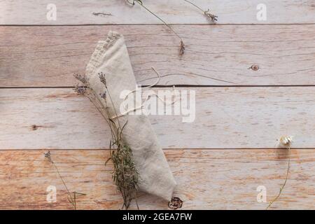 Folded a natural color linen dinner napkin and dry lavender sprigs on wooden table. Top view, copy space, flat lay, space for text. Stock Photo