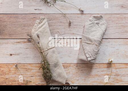 Folded a natural color linen dinner napkin and dry lavender sprigs on wooden table. Top view, copy space, flat lay, space for text. Stock Photo